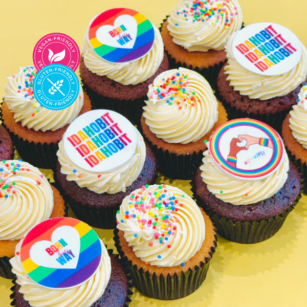 Gluten-friendly and vegan-friendly regular-sized cupcakes topped with IDAHOBIT fondant discs and colourful sprinkles on a yellow backdrop.