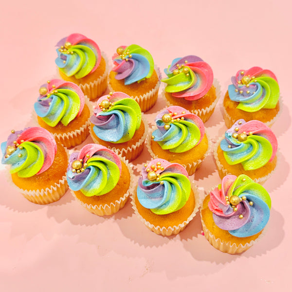 Mini cupcakes topped with pastel rainbow buttercream and gold pearls, available in vanilla, chocolate, or both. Ideal for unicorn-themed parties.