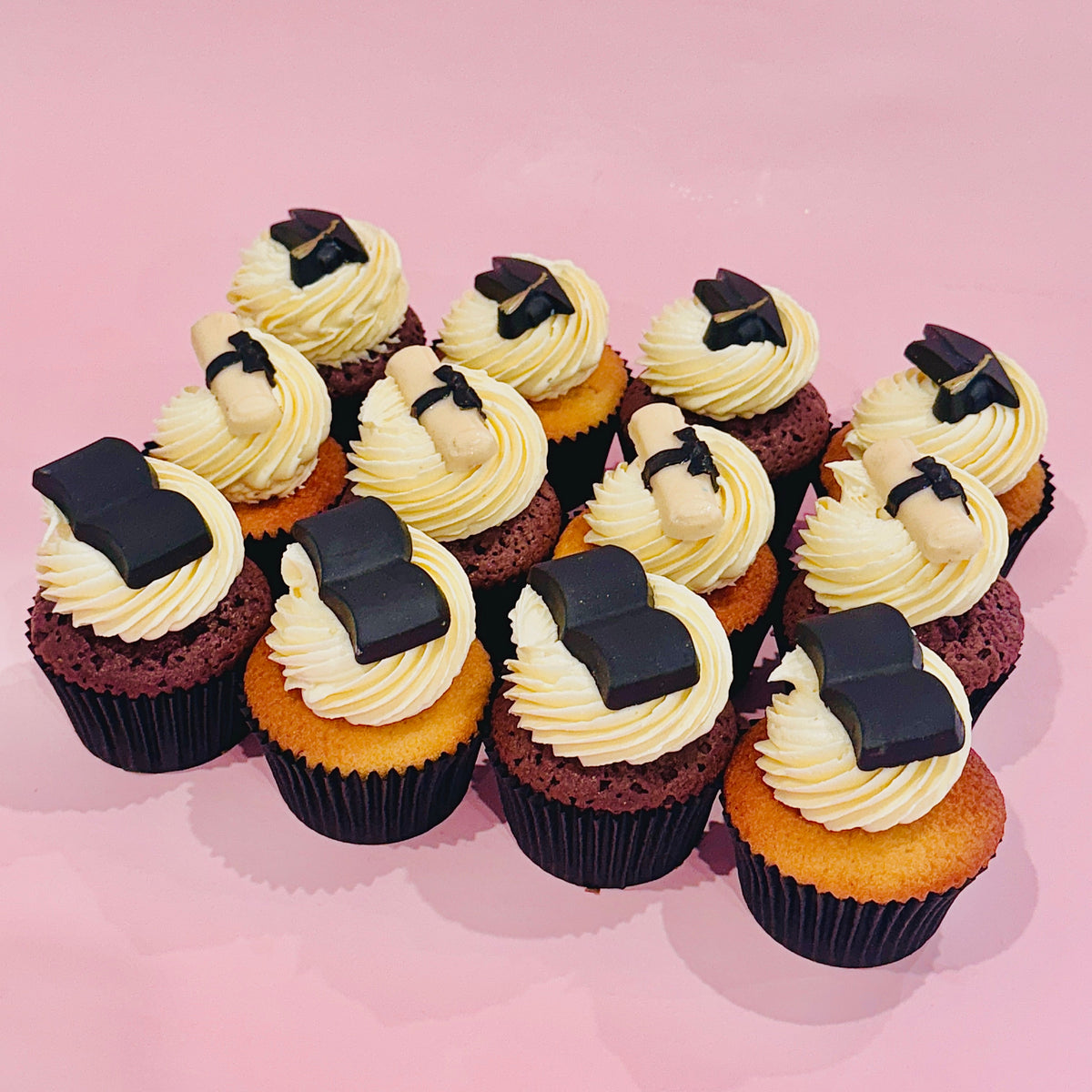Graduation-themed cupcakes topped with chocolate caps and diplomas from Sugar Rush Bakery