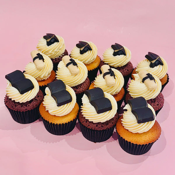 Graduation-themed cupcakes topped with chocolate caps and diplomas from Sugar Rush Bakery