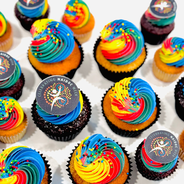 Colorful cupcakes with rainbow frosting on a white surface