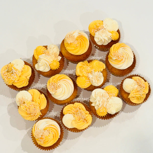 Assorted cupcakes with yellow and white frosting on a light background